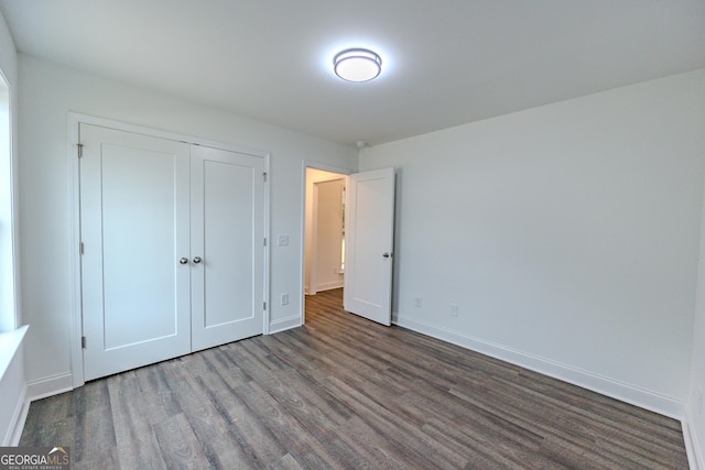 unfurnished bedroom with wood finished floors, baseboards, and a closet