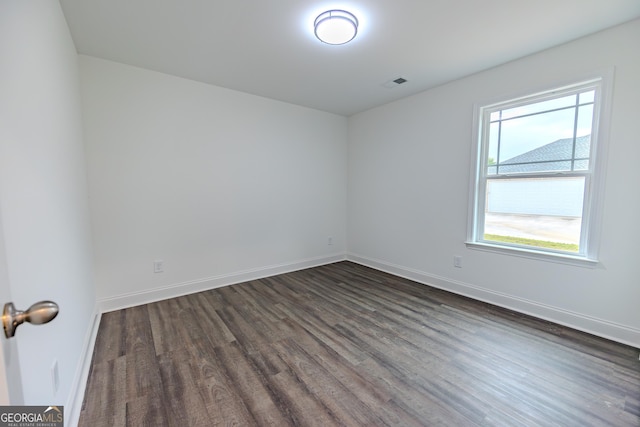 empty room with dark wood-style flooring and baseboards