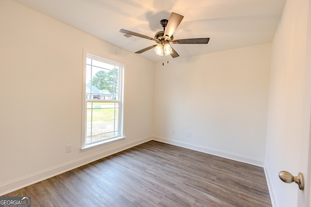 spare room with dark wood-type flooring, a ceiling fan, and baseboards