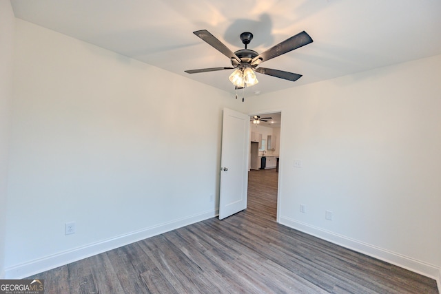 empty room with ceiling fan, dark wood-style flooring, and baseboards