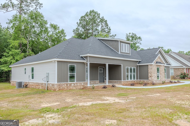 view of front of property with a shingled roof, a front lawn, and brick siding