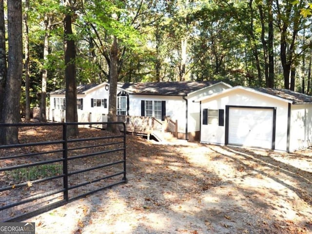 ranch-style home featuring fence, an attached garage, a gate, and dirt driveway