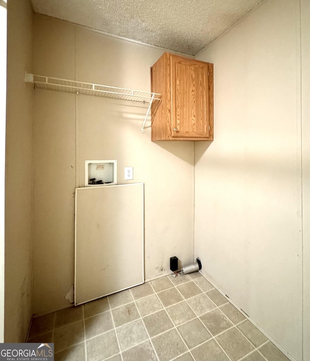 clothes washing area featuring cabinet space, washer hookup, a textured ceiling, and tile patterned floors