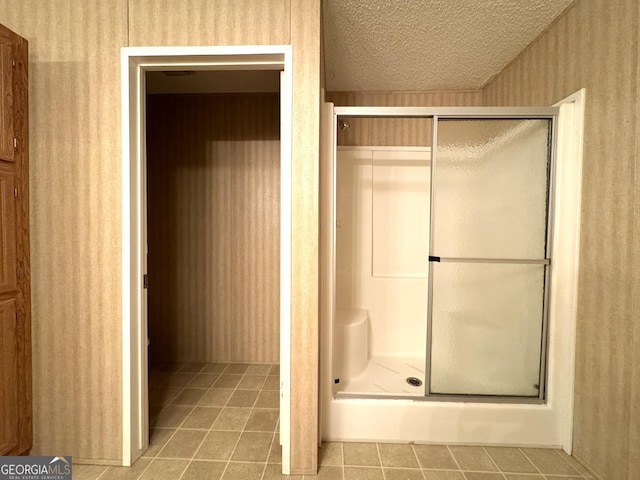 full bath with tile patterned flooring, a shower stall, and a textured ceiling