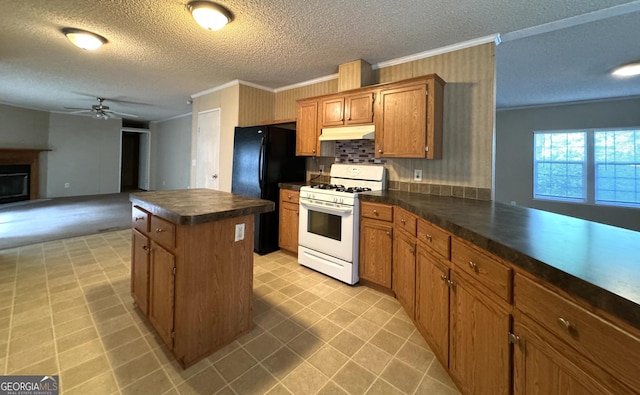 kitchen with white range with gas cooktop, under cabinet range hood, ornamental molding, a kitchen island, and dark countertops