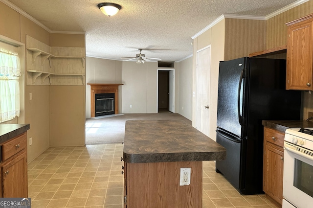 kitchen featuring dark countertops, white gas range oven, a ceiling fan, crown molding, and a kitchen island