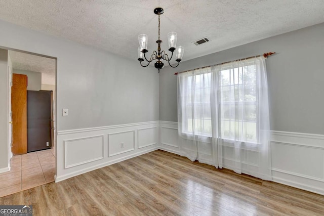 2355 Glen Chase Ln, Lawrenceville, GA 30044 - empty room with a chandelier, a textured ceiling, wood finished floors, a wainscoted wall, and a decorative wall