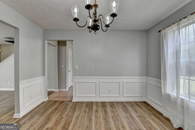 2355 Glen Chase Ln, Lawrenceville, GA 30044 - unfurnished dining area with a chandelier, a textured ceiling, wood finished floors, and wainscoting