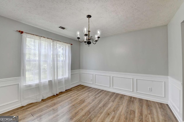 2355 Glen Chase Ln, Lawrenceville, GA 30044 - empty room with a chandelier, wood finished floors, wainscoting, a textured ceiling, and a decorative wall