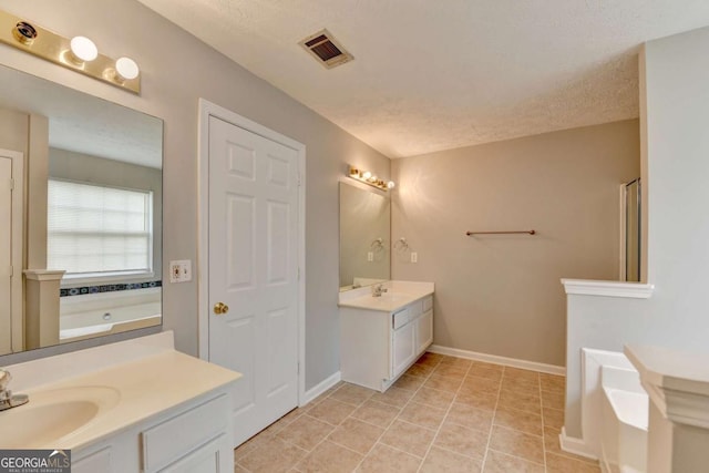 2355 Glen Chase Ln, Lawrenceville, GA 30044 - bathroom featuring a garden tub, two vanities, baseboards, tile patterned flooring, and a textured ceiling