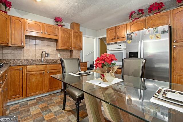 2950 Springfield Ct SW, College Park, GA 30349 - kitchen featuring stainless steel fridge, a sink, brown cabinetry, and a textured ceiling
