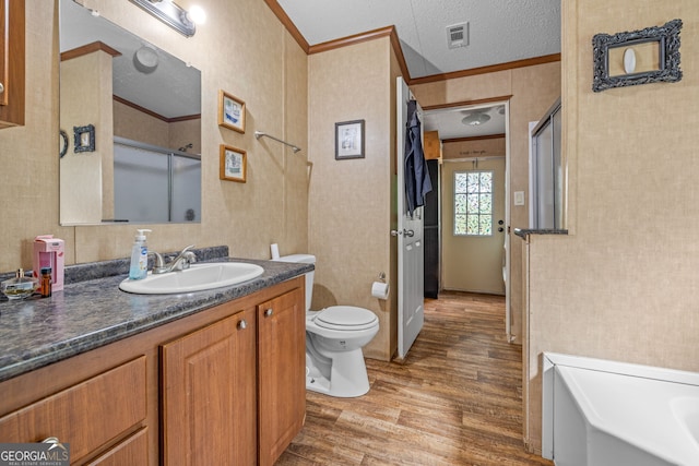 bathroom with wood finished floors, ornamental molding, a shower with door, toilet, and vanity