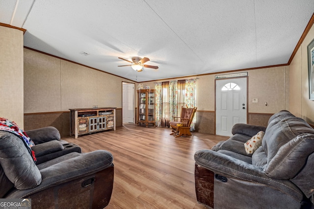 living area featuring ornamental molding, wood finished floors, a ceiling fan, a textured ceiling, and a wainscoted wall