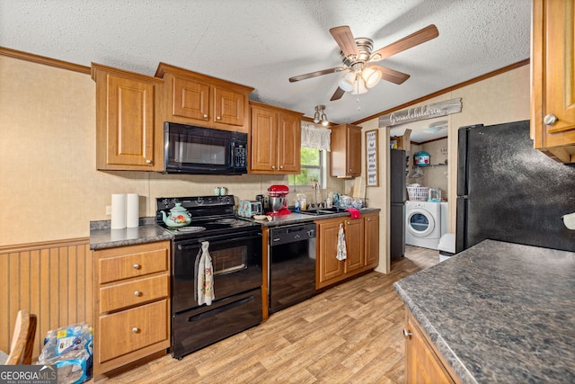 kitchen featuring black appliances, a sink, crown molding, dark countertops, and washer / dryer