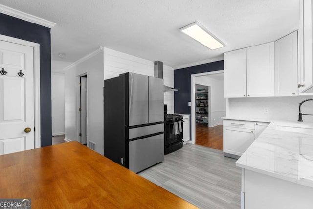 kitchen featuring freestanding refrigerator, black gas stove, a sink, ornamental molding, and light wood-style flooring