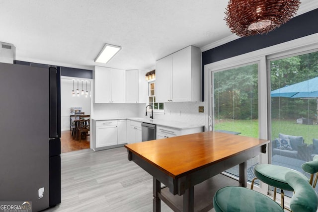kitchen with freestanding refrigerator, dishwasher, light countertops, white cabinets, and light wood-type flooring