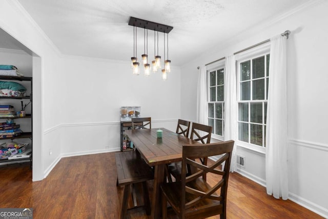 dining area featuring wood finished floors, crown molding, a chandelier, and baseboards