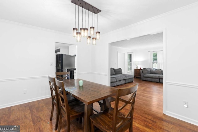 dining space featuring wood finished floors, crown molding, a chandelier, and baseboards