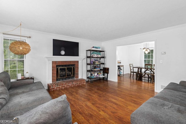 living area with crown molding, healthy amount of natural light, wood finished floors, and a fireplace