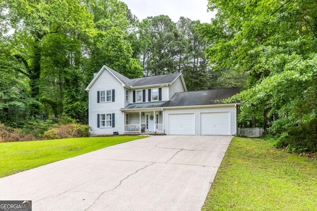 traditional-style house with a porch, an attached garage, driveway, and view of wooded area