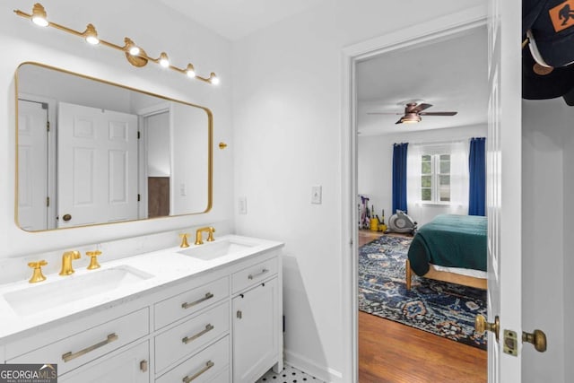 full bath featuring ensuite bath, double vanity, a ceiling fan, and wood finished floors