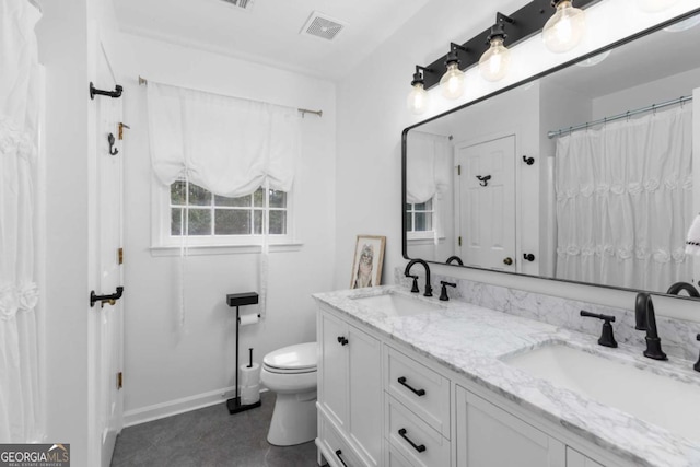 full bath with toilet, double vanity, and baseboards