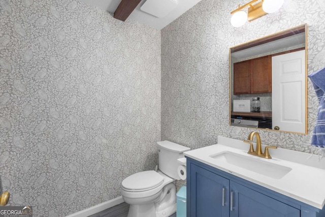bathroom featuring toilet, vanity, and beamed ceiling