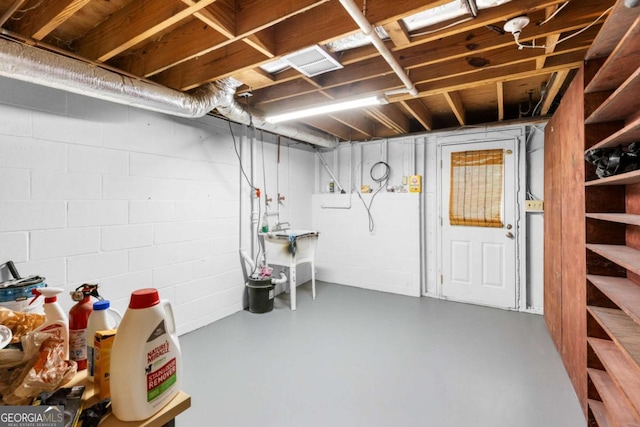 unfinished below grade area with concrete block wall, a sink, and stairs