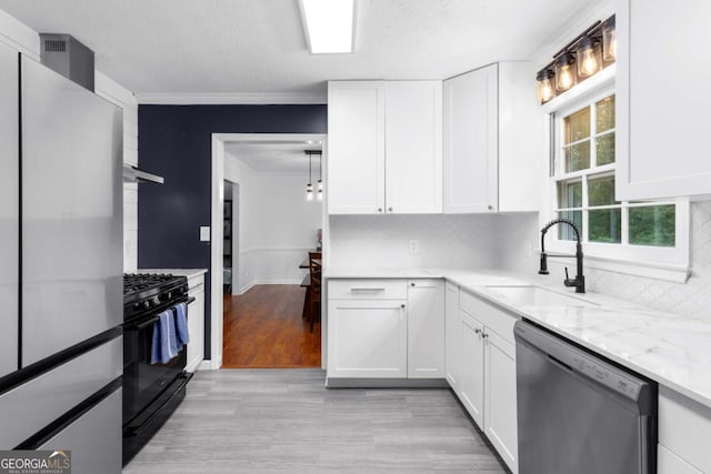 kitchen featuring dishwasher, black gas range oven, a sink, white cabinets, and light wood-style floors
