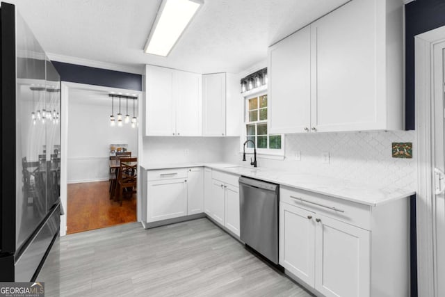 kitchen featuring appliances with stainless steel finishes, a sink, white cabinetry, decorative backsplash, and light wood-style flooring