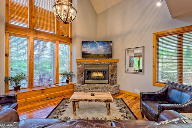 living area with wood-type flooring, a chandelier, healthy amount of natural light, a fireplace, and high vaulted ceiling