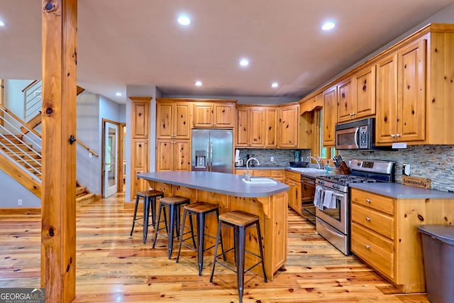 kitchen with stainless steel appliances, a sink, light wood-type flooring, tasteful backsplash, and recessed lighting