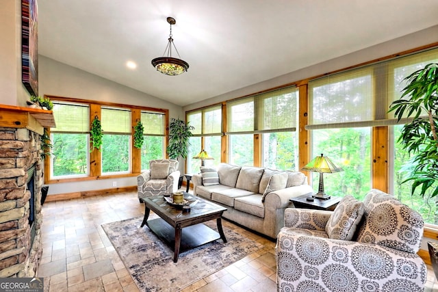 living area featuring vaulted ceiling and a stone fireplace