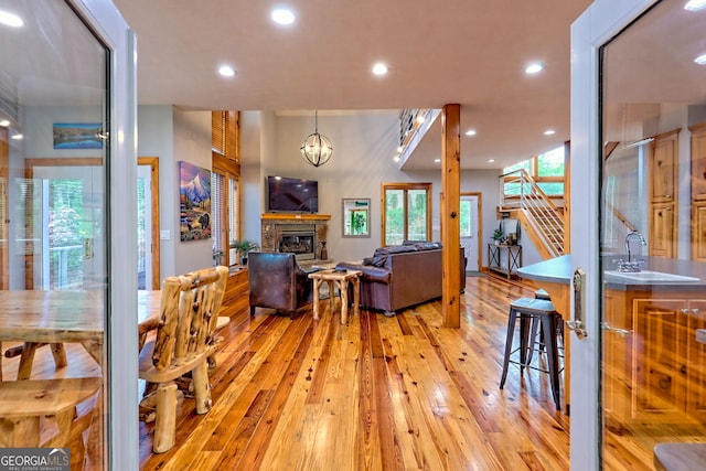 living area featuring light wood-type flooring, a stone fireplace, recessed lighting, and stairs