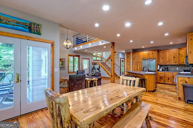 dining area featuring light wood-type flooring, recessed lighting, stairs, and a chandelier