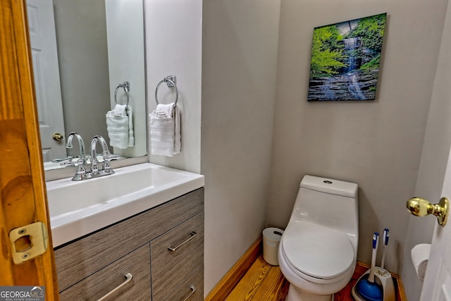 bathroom featuring toilet, baseboards, and vanity