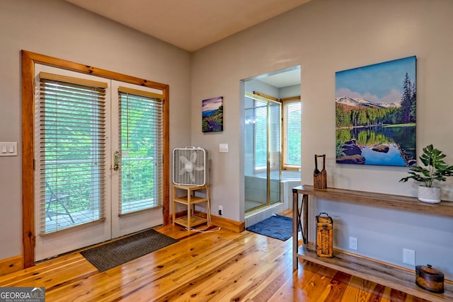 doorway to outside with wood finished floors, healthy amount of natural light, and baseboards