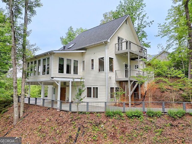 back of house featuring a balcony, fence, a patio area, and roof with shingles