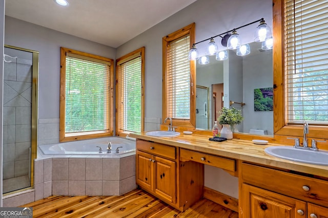 full bathroom with a stall shower, wood finished floors, a garden tub, and double vanity