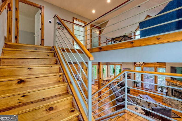 stairway with a high ceiling, recessed lighting, and wood finished floors