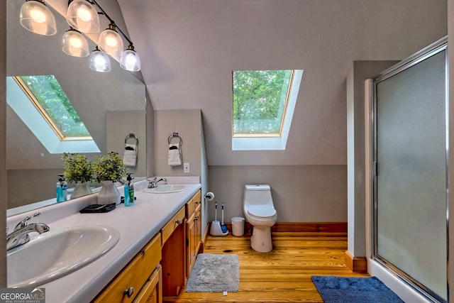 bathroom with a skylight, wood finished floors, toilet, a shower stall, and double vanity
