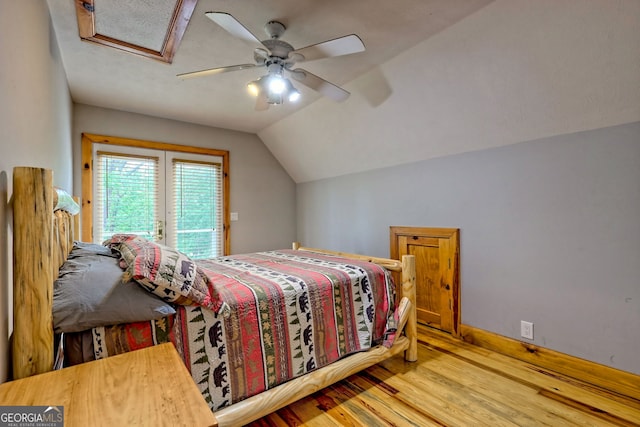 bedroom featuring access to exterior, wood finished floors, lofted ceiling, a ceiling fan, and baseboards