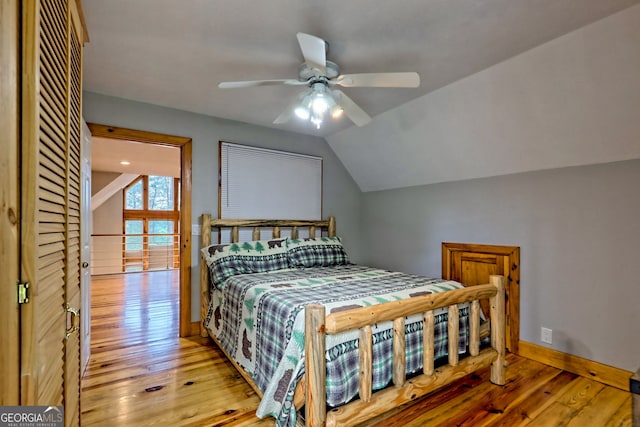 bedroom with light wood finished floors, baseboards, vaulted ceiling, and ceiling fan