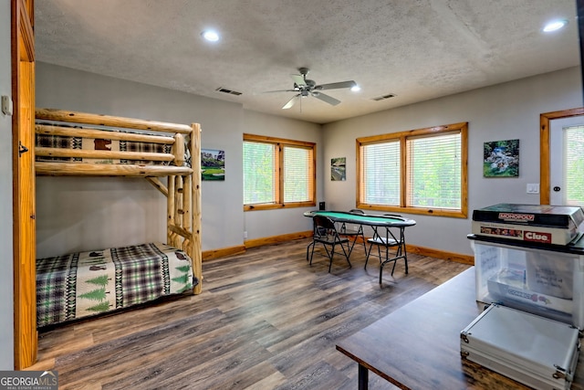 bedroom featuring baseboards, wood finished floors, recessed lighting, multiple windows, and a textured ceiling