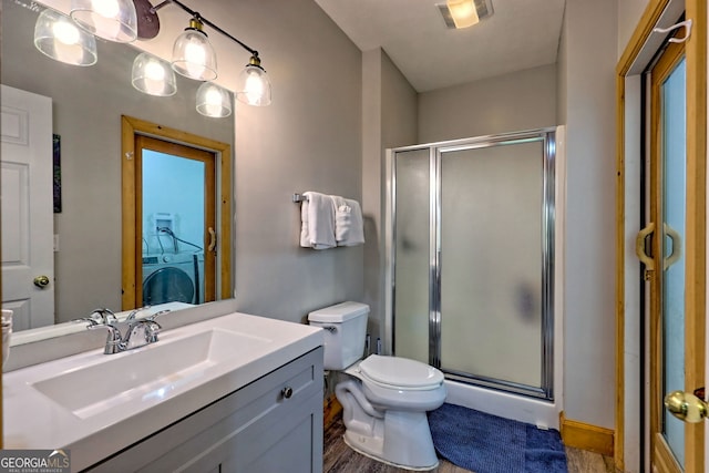 bathroom featuring washer / dryer, a shower stall, vanity, and toilet