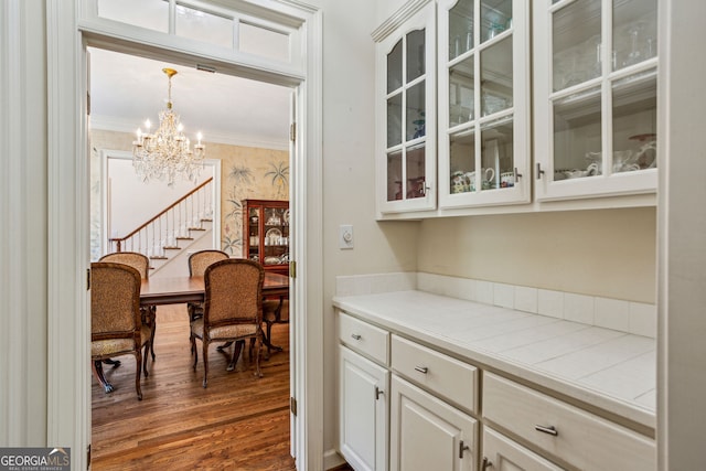 4070 Ridgehurst Dr SE, Smyrna, GA 30080 - bar area with dark wood-type flooring, a chandelier, crown molding, and pendant lighting