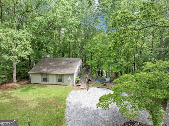 view of front of home with a chimney, a front yard, and a forest view