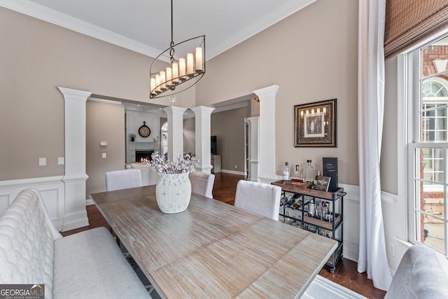 1610 Turtle Pond Dr, Hoschton, GA 30548 - dining area featuring decorative columns, a fireplace, dark wood finished floors, a wainscoted wall, and crown molding