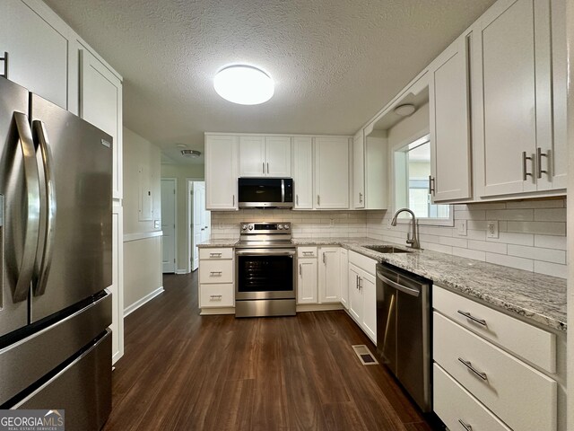 485 Angham Rd, Hiram, GA 30141 - kitchen featuring appliances with stainless steel finishes, white cabinetry, dark wood-style flooring, light stone counters, and a textured ceiling