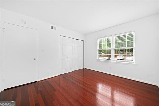 52 Chaumont Sq NW, Atlanta, GA 30327 - unfurnished bedroom featuring wood finished floors, baseboards, and a closet